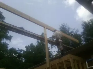 Carpenter setting a ridge beam over a new addition frame — Ice Dam Removal by Roofing Brothers in Summerton