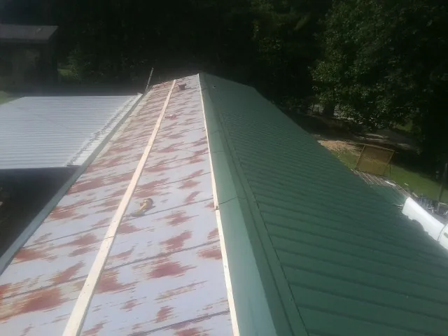 Old rusted panels beside newly installed green metal roofing — Wind Damage Roof Repair by Roofing Brothers in Summerton