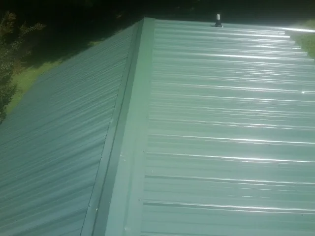 New green metal panels meeting at the ridge of a roof — Flat Roof Repair work by our crew in Summerton