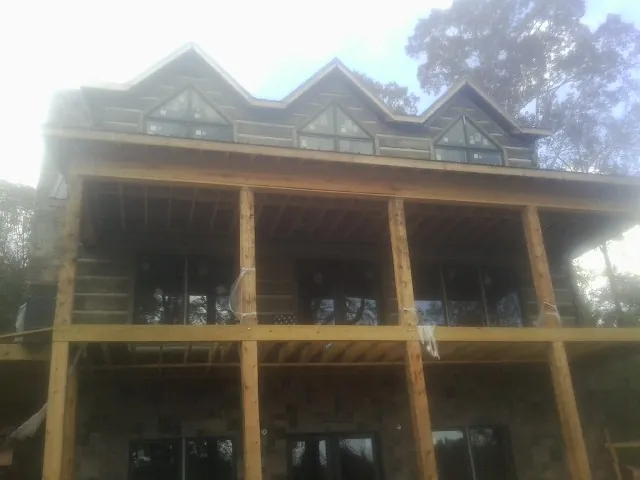 Dormers and porch framing on a large log home under construction — Roof Coating work by our crew in Summerton
