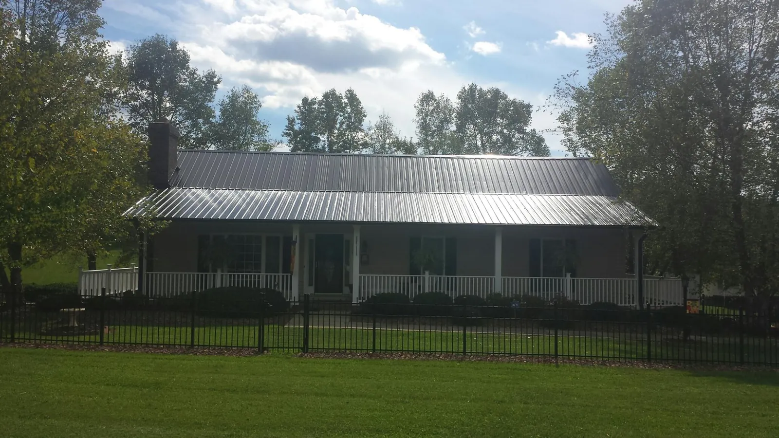 Gray metal roof on a brick ranch with a full width front porch — Gutter Guard Installation work by our crew in Summerton